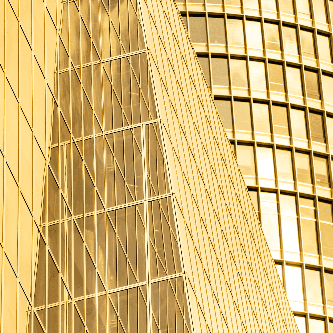 Modern glass and steel building with a golden hue reflecting sunlight.
