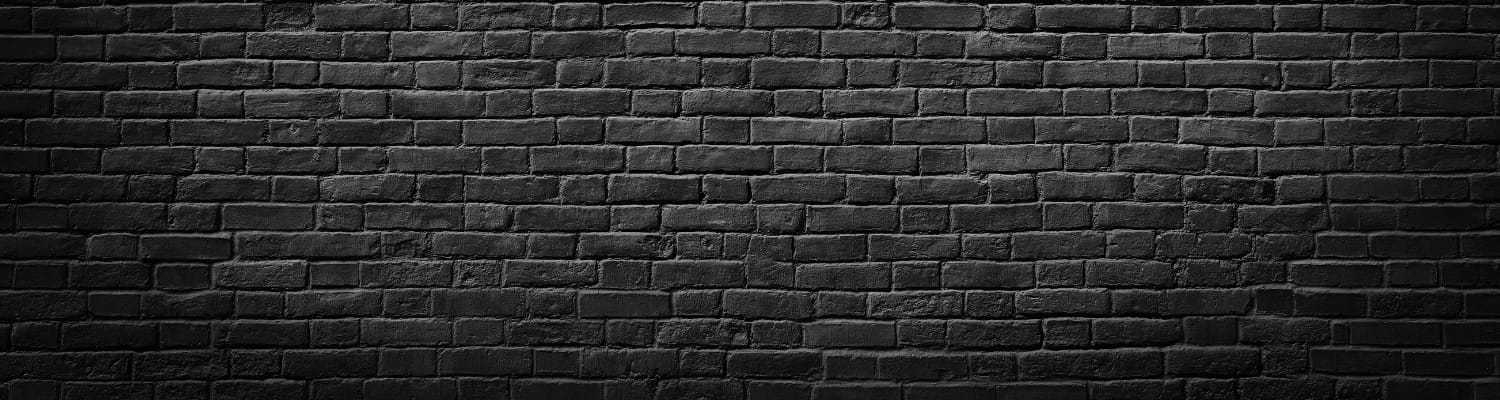Dark brick wall with uneven texture and shadows across the surface.